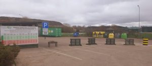 Laukumā atkritumu konteineri. Bildes dziļumā atkritumu kalns.